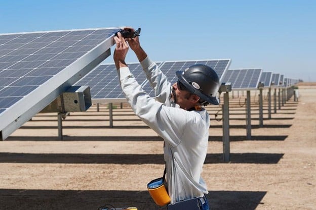 man reaching to side of solar panel 