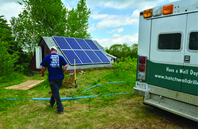 A technician from Hatch Well Drilling services the solar arrays
